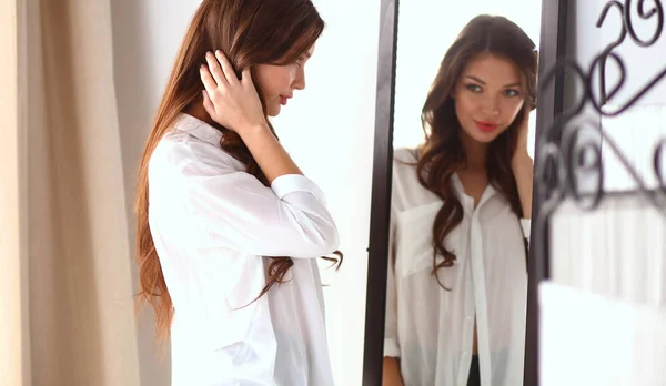 Giovane donna guardando se stessa riflesso nello specchio a casa — Foto Stock