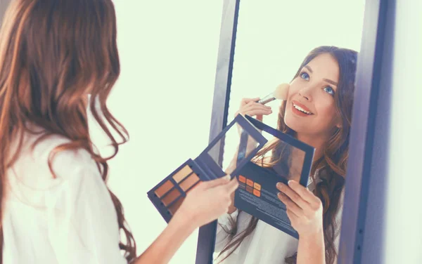 Junge schöne Frau schminkt sich in Spiegelnähe — Stockfoto