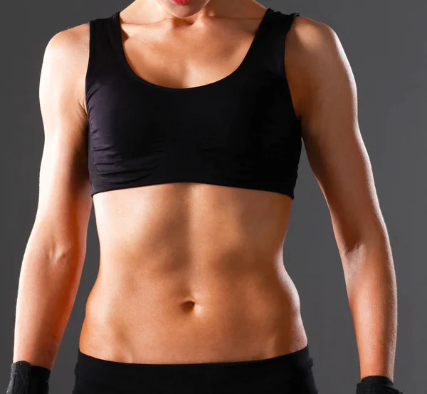 Muskulös ung kvinna stående på grå bakgrund — Stockfoto