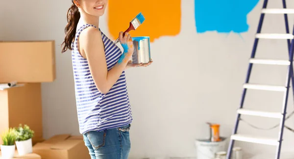 Happy smiling woman painting interior wall of new house