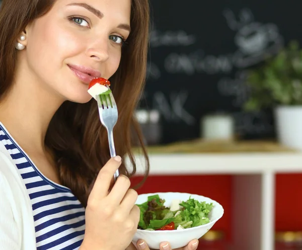 Jeune femme mangeant de la salade et tenant une salade mixte — Photo