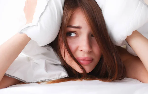 Female lying on bed and closing her ears with pillow — Stock Photo, Image