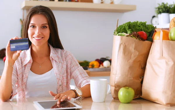 Lächelnde Frau beim Online-Shopping mit Tablet und Kreditkarte in der Küche — Stockfoto