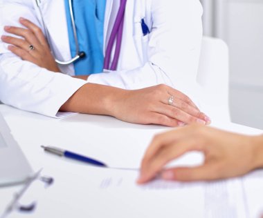 Doktor ve hasta ofiste masada oturuyorlar.