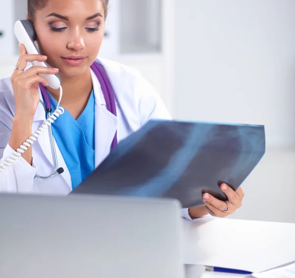 Doctora joven estudiando imagen de rayos X sentada en el escritorio — Foto de Stock