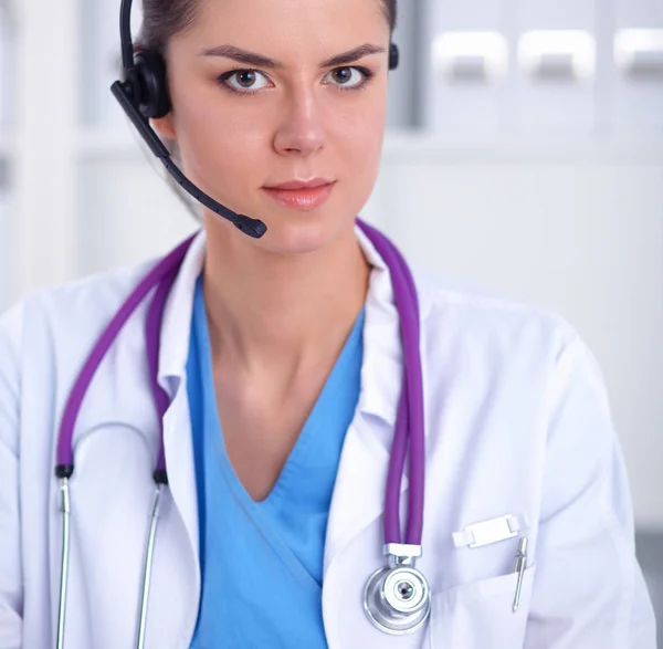 Médico con auriculares sentado detrás de un escritorio con portátil —  Fotos de Stock