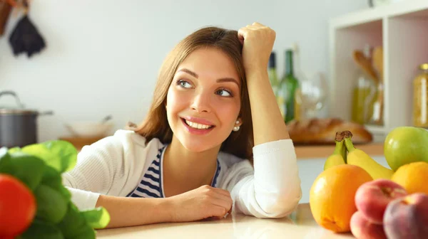 Jovem mulher de pé perto da mesa na cozinha — Fotografia de Stock