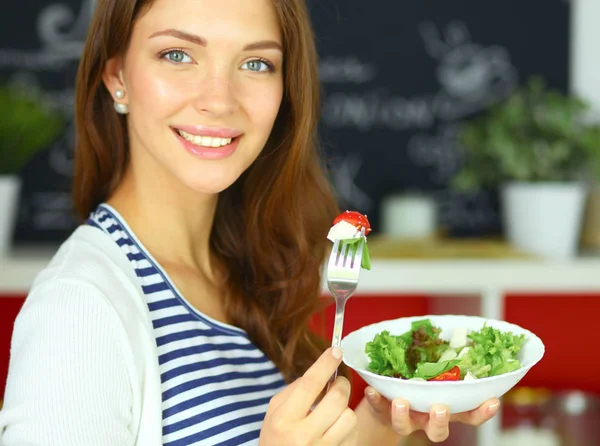 Junge Frau isst Salat und hält eine gemischte — Stockfoto