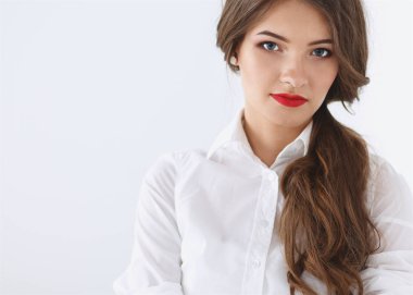 Ofiste duvarın yanında duran çekici bir iş kadını.