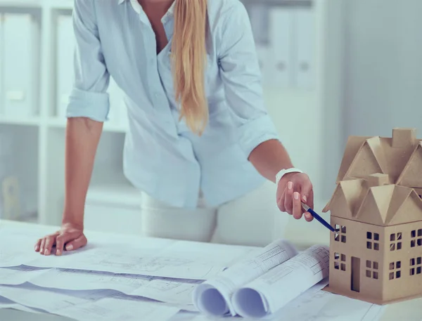 Portrait of female architect with blueprints at desk in office — Stock Photo, Image