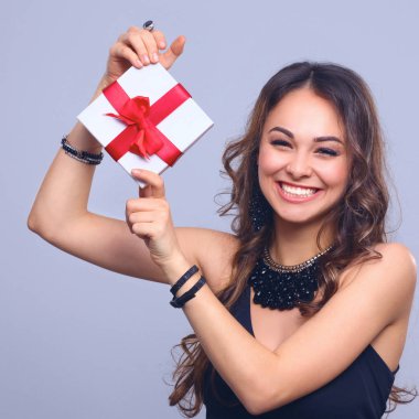 genç kadın mutlu gülümseme hediye kutusu gri arka plan üzerinde izole elinde tut