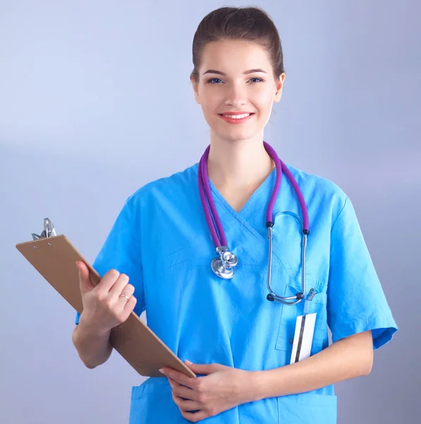 Улыбающаяся женщина-врач с папкой в форме, стоящей в больнице — стоковое фото