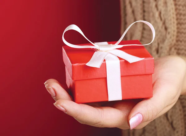 Female hand holding gift box isolated on red background — Stock Photo, Image