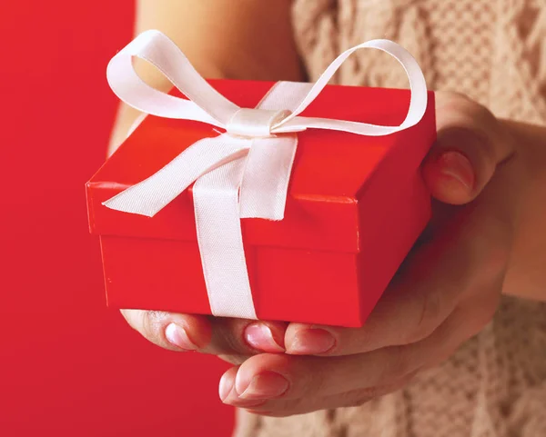 Caja de regalo de mano femenina aislada sobre fondo rojo — Foto de Stock