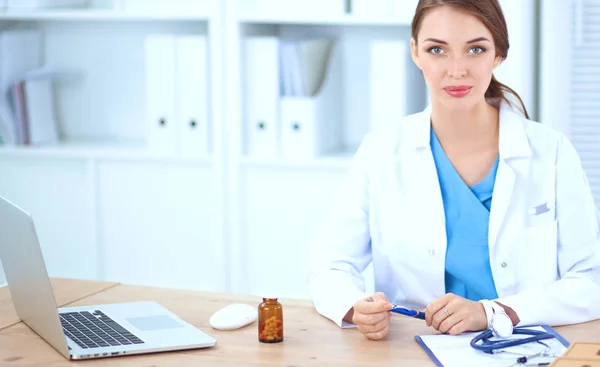 Belle jeune femme médecin souriante assise au bureau et écrivant. — Photo