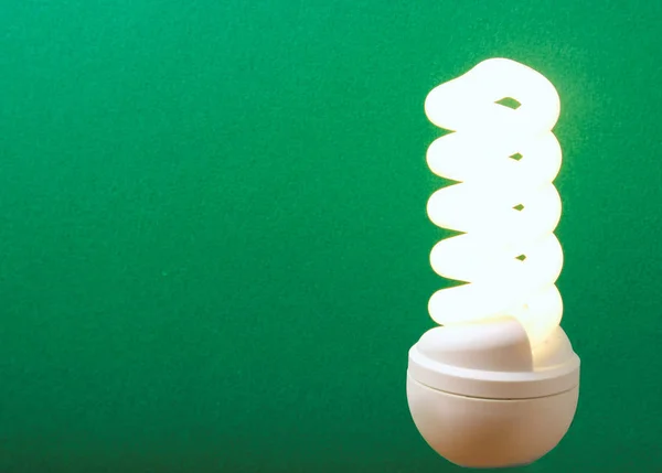 Electrical fluorescent energy-saving lamp isolated on green background — Stock Photo, Image