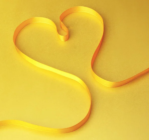 Uma fita amarela moldando o coração — Fotografia de Stock