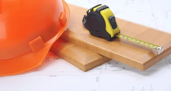 An orange hardhat with a ruler on wooden planks — Stock Photo, Image