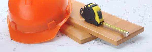 An orange hardhat with a ruler on wooden planks — Stock Photo, Image