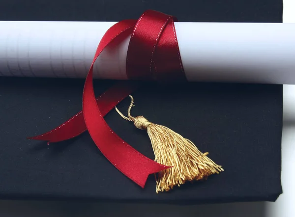 Um diploma universitário com uma fita vermelha isolada em branco — Fotografia de Stock