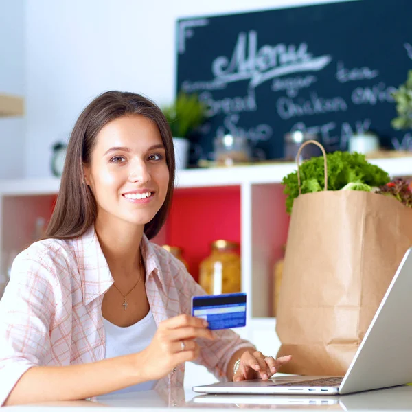 Femme souriante achats en ligne en utilisant tablette et carte de crédit dans la cuisine — Photo