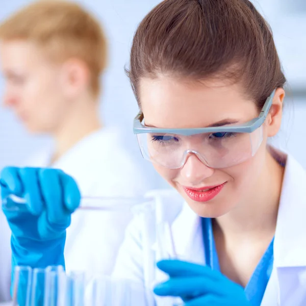 Woman researcher is surrounded by medical vials and flasks, isolated on white background — Stock Photo, Image