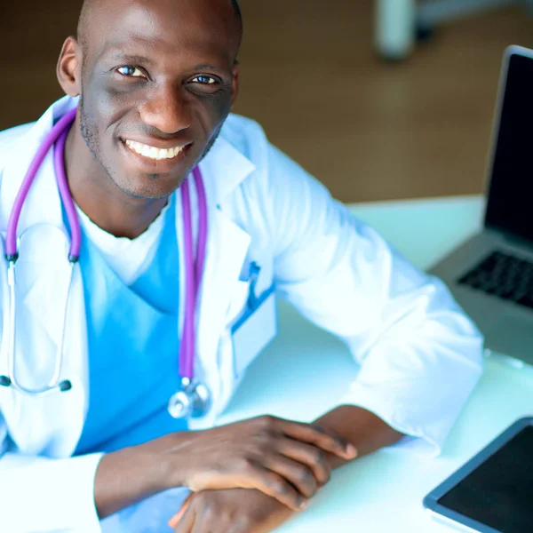 Young african doctor working on laptop at desk