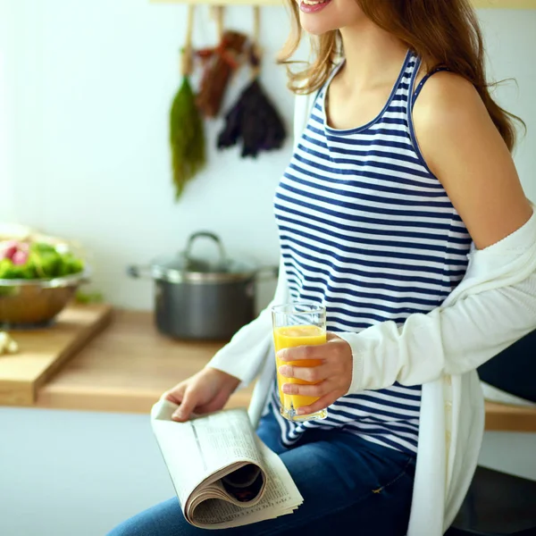 Genç bayan mutfakta masanın yanında oturuyor.