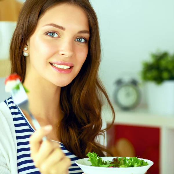 Mujer joven comiendo ensalada y sosteniendo una mezcla — Foto de Stock