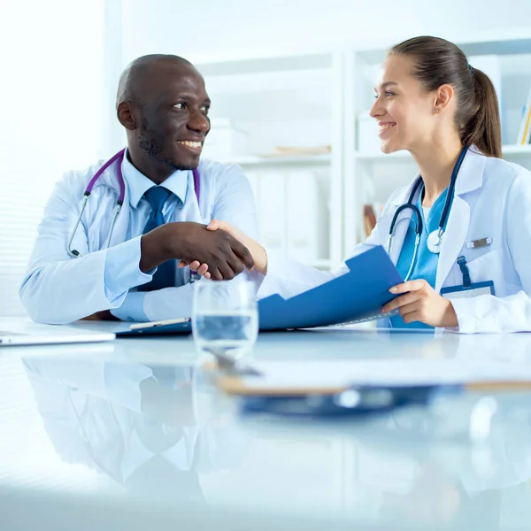 Ofiste tokalaşırken gülümseyen iki genç doktor.