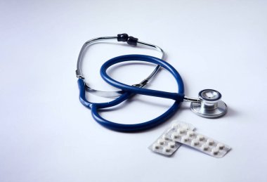 Stetoskop ve beyaz arka planda izole edilmiş bazı haplar.