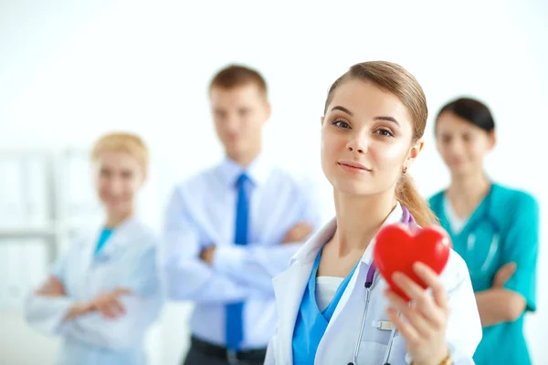 Mujer joven doctora sosteniendo un corazón rojo, aislado sobre fondo blanco — Foto de Stock