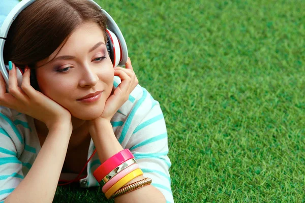 Vrouw luisteren naar de muziek zitten op gras — Stockfoto