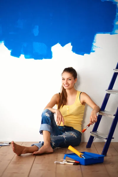 Retrato de pintora sentada en el suelo cerca de la pared después de pintar —  Fotos de Stock