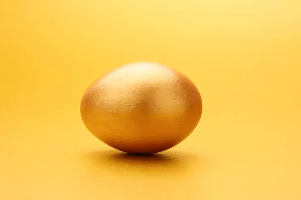 Zlaté vejce na žlutém podkladu — Stock fotografie
