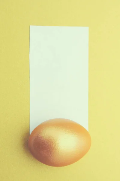 Gouden ei op gele achtergrond — Stockfoto