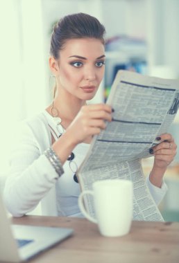 parlak ofis masasında oturup gazete tutan şirin iş kadını
