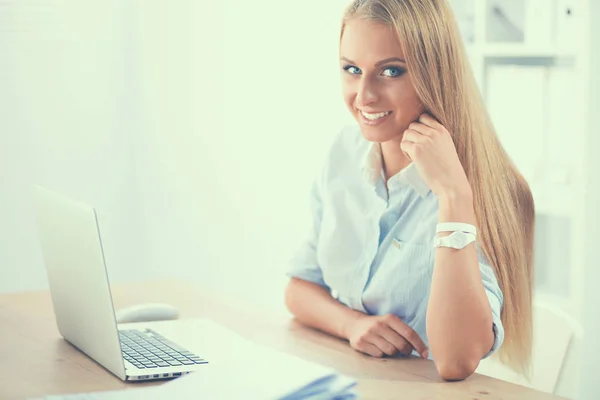 Aantrekkelijke zakenvrouw zit op een bureau met laptop in het kantoor — Stockfoto