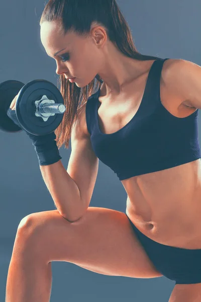 Mujer atlética bombeando músculos con mancuernas — Foto de Stock