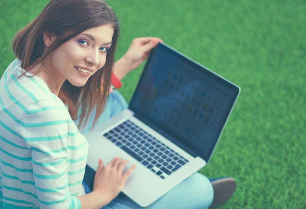 Giovane donna con computer portatile seduto su erba verde — Foto Stock