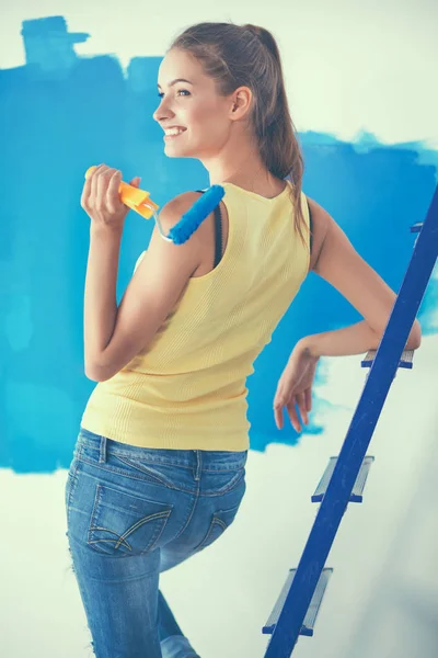 Happy beautiful young woman doing wall painting, standing near ladder — Stock Photo, Image