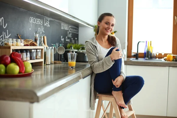 Ung kvinna sitter ett bord i köket . — Stockfoto