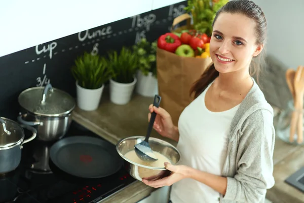 Mujer joven cocinando panqueques en la cocina de pie cerca de la estufa —  Fotos de Stock