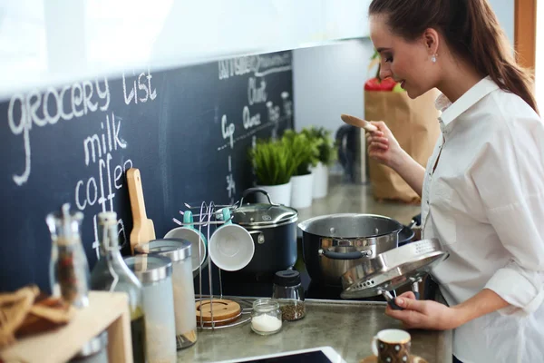 Mujer joven parada junto a la estufa en la cocina — Foto de Stock