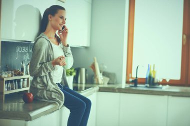 modern mutfakta otururken cep telefonu kullanan kadın