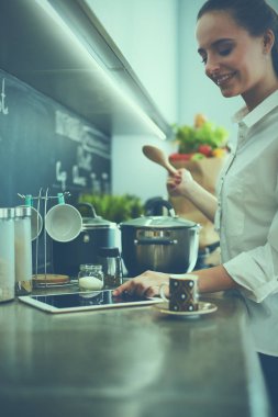 Mutfakta sobanın yanında duran genç bir kadın.