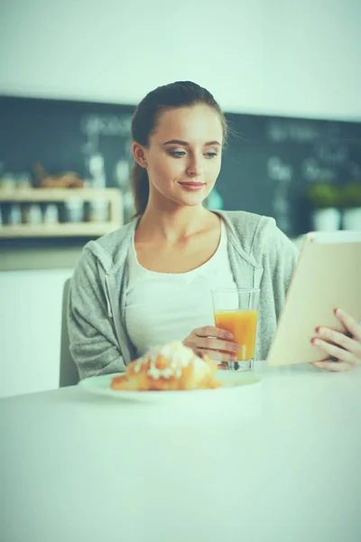 Jeune femme avec jus d'orange et tablette dans la cuisine — Photo