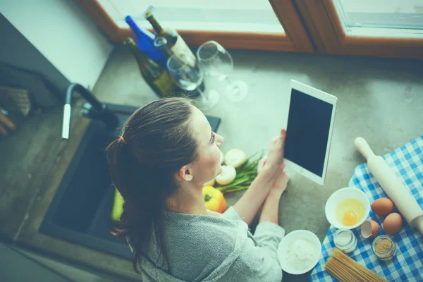 Tablette tarifi takip eden bir kadın evde yemek pişiriyor. — Stok fotoğraf