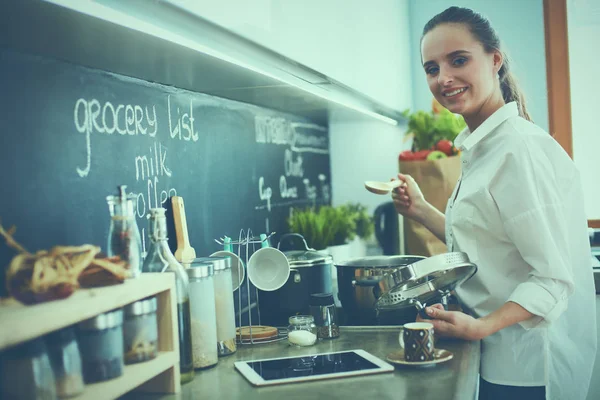 Junge Frau steht am Herd in der Küche — Stockfoto