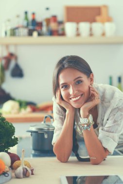 Mutfakta masanın yanında duran genç bir kadın.